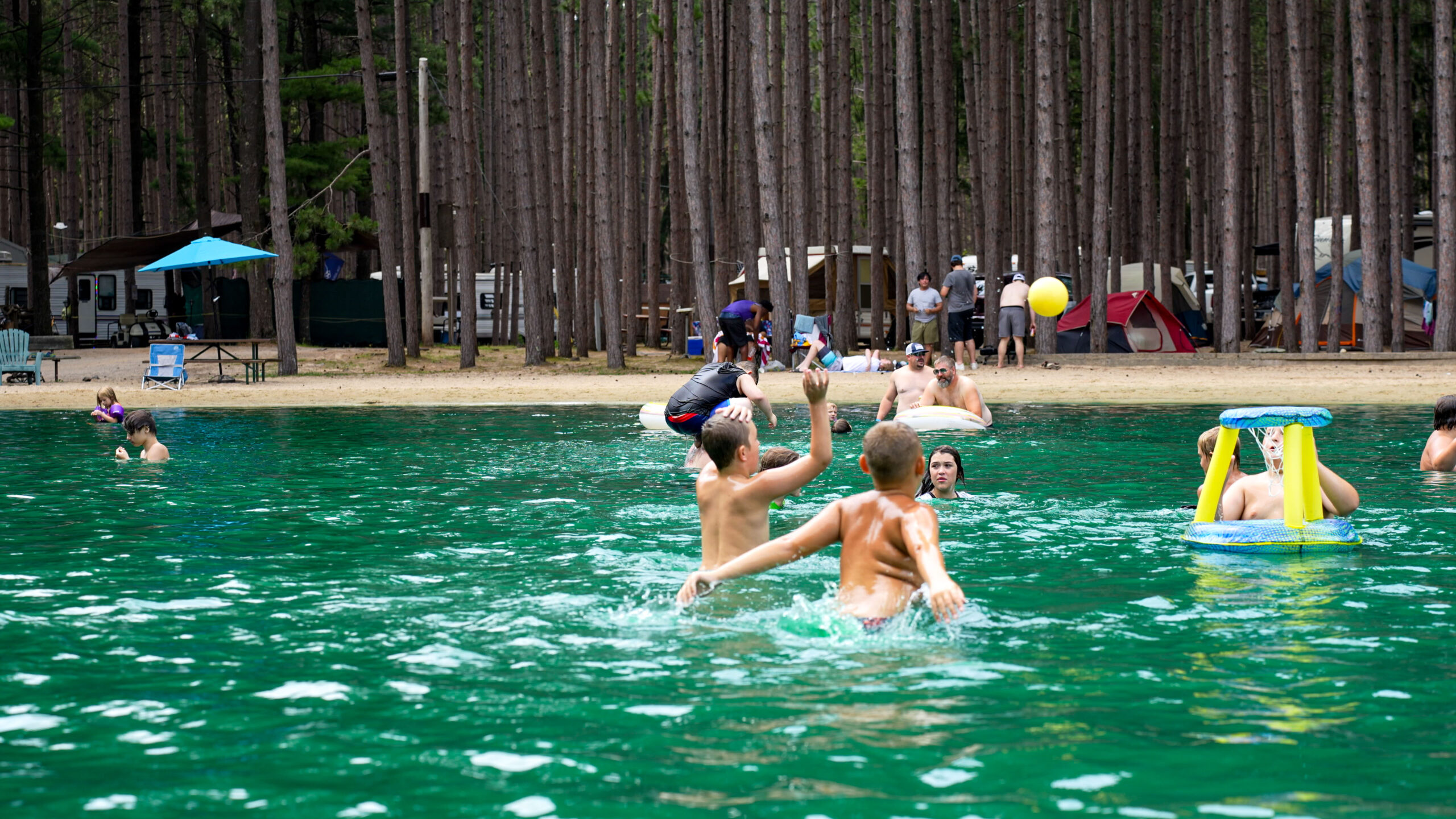 Seasonal Campers and kids gathered at the swimming pond and sand beach at Pearl Lake RV Campground.