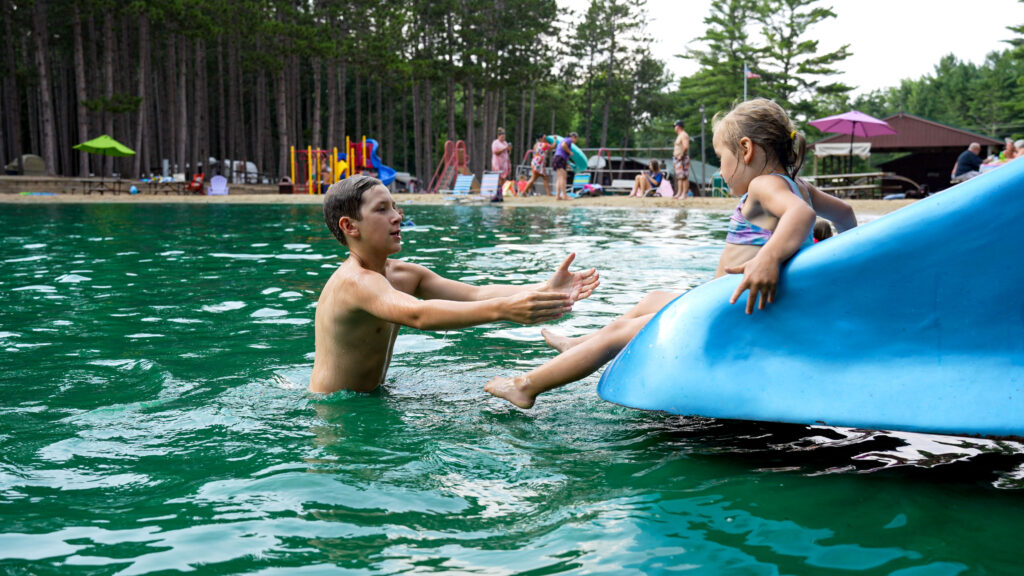 A young father catches his daughter at the bottom of the slide at Pearl Lake's Swimming Basin.