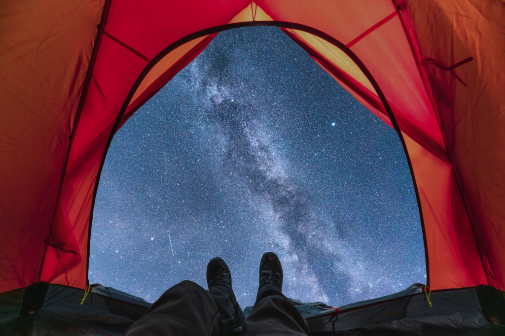 A camper looks out the open flap of his tent to see the milky way.